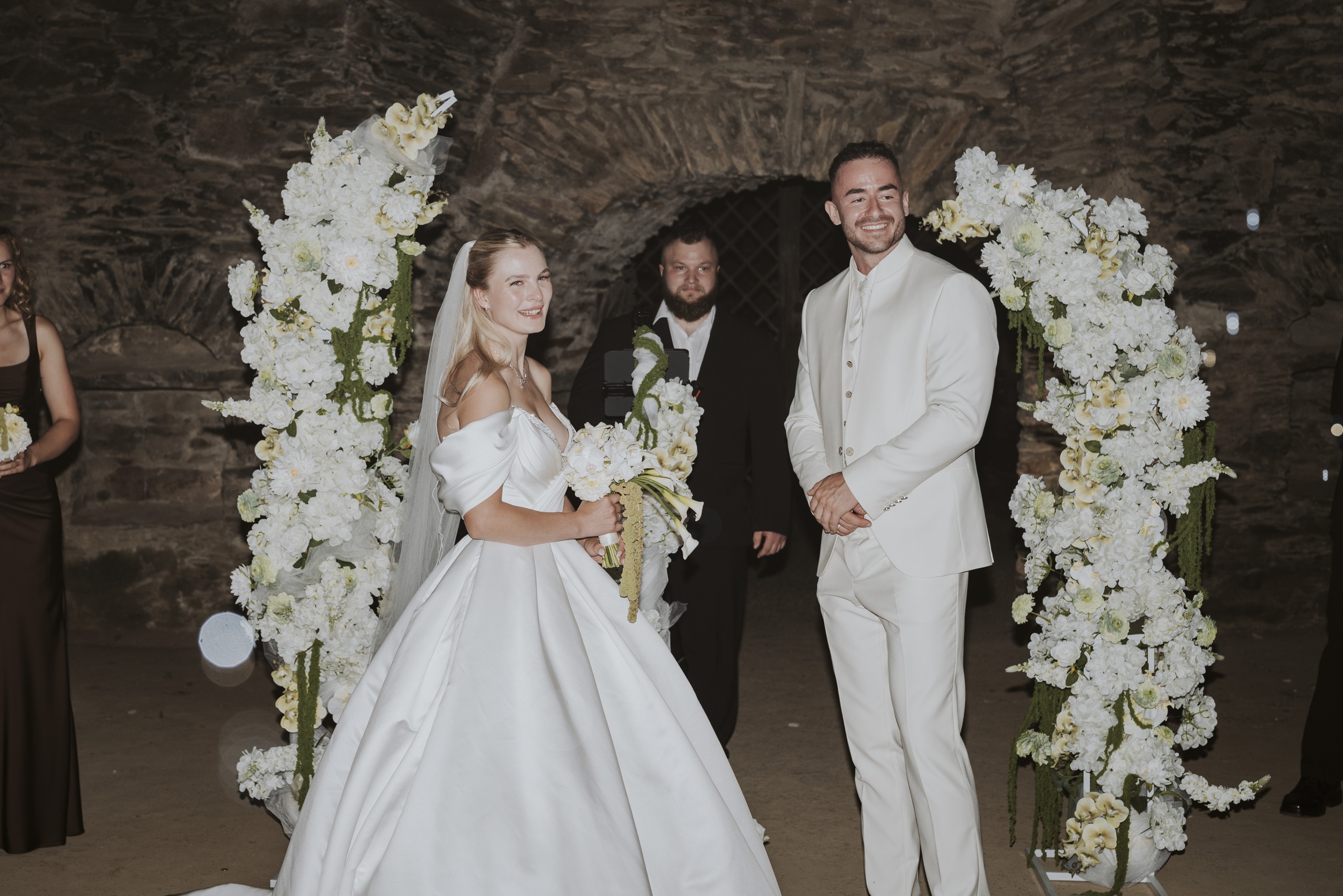 Nadja und Lucas während ihrer Trauung vor dem weißen Blumenbogen.