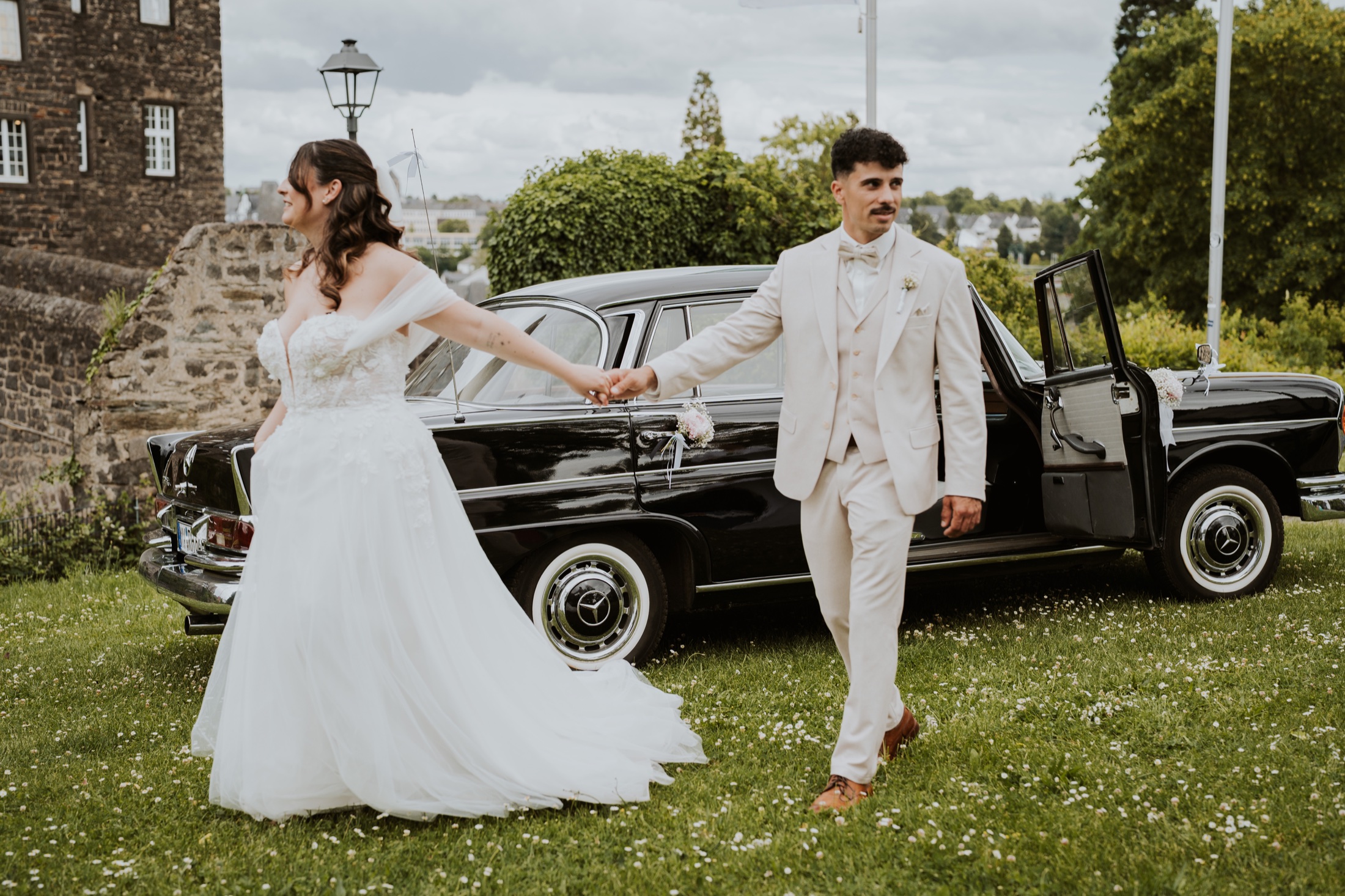 Ein Brautpaar vor seinem historischen Hochzeitsauto.
